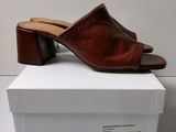 a pair of brown leather mulers on top of a white box