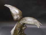 bronze statue of a bird with wings spread out on a black surface