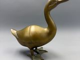 a brass duck figurine sitting on a white surface