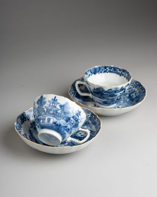 two blue and white cups and saucers on a table
