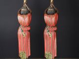 two red and black ceramic figurines of women with hats on their heads