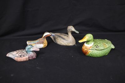 three small ceramic ducks sitting on top of each other on a black surface