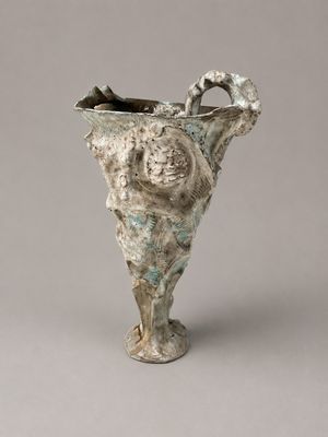 un petit vase orné d'un visage, posé sur une table