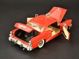 a red toy car with its open hood open on a black surface