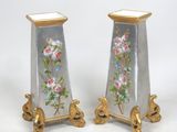 une paire de vases décorés de fleurs, posés sur une surface blanche