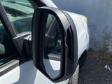 a side view mirror of a white truck parked in a parking lot