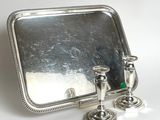 a silver tray with two candles and a mirror on it