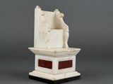 a white marble statue of a man sitting on top of a table