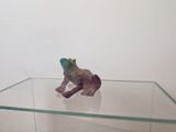 figurine de grenouille violette assise sur une table en verre, coiffée d'une couronne