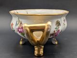 a white bowl with a gold handle on a black table