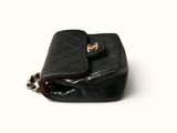 black quilted purse with chain strap on a white background