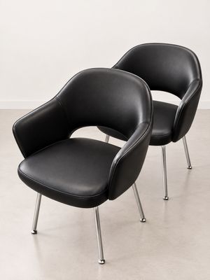 une paire de fauteuils en cuir noir aux pieds chromés dans une pièce blanche