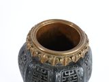 a black and gold vase sitting on a white surface