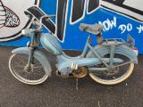 a old blue motorcycle parked in front of a graffiti covered wall