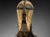 un masque en bois avec de longs cheveux et un visage sculpté dans le bois