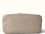 the large beige bag is sitting on a white surface