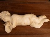 a small statue of a baby laying on a wooden table