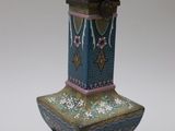 a vase that is sitting on a stand on a white surface