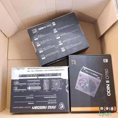 trois boîtes contenant des gadgets électroniques, empilées les unes sur les autres dans un carton