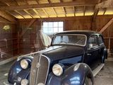 une vieille voiture bleue dans un garage au plafond en bois