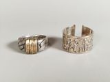 two silver rings with gold bands on a white surface