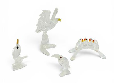 trois figurines blanches représentant des oiseaux et un oiseau perché sur une branche