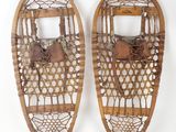 pair of old snowshoes on a white surface with a white background