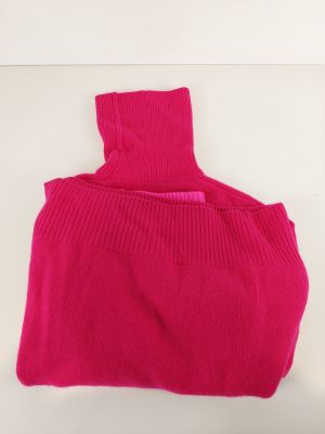 un pull à col roulé rose posé sur une surface blanche