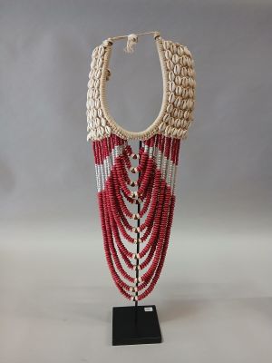un gros plan d'un collier posé sur un support, sur une surface blanche