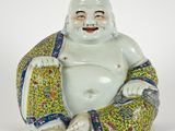 une statue représentant un Bouddha souriant, assis sur un coussin