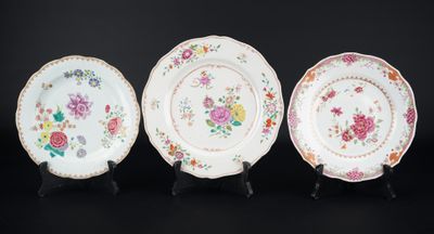 three plates with floral designs on them sitting on a black surface