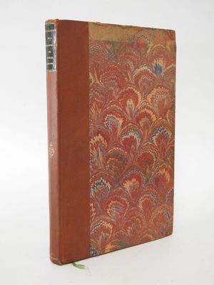 an old book with a red cover sitting on top of a white surface