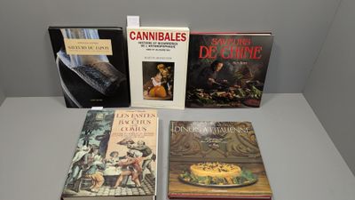 Plusieurs livres sont posés sur une table devant un mur blanc.