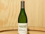 une bouteille de vin posée sur un tonneau en bois