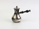 une théière ancienne en argent, avec une anse noire sur fond blanc