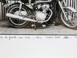 a black and white photo of a man standing next to a motorcycle