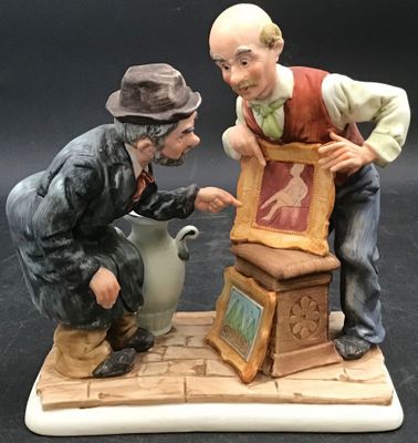 a figurine of two men sitting on top of a box