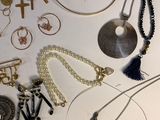 many different necklaces and earrings on the table