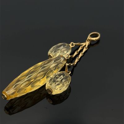 deux feuilles en verre jaune suspendues à une chaîne dorée sur une surface noire