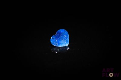 une pierre bleue en forme de cœur posée sur une surface noire