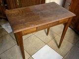 une table en bois avec un tiroir en dessous, posée sur un sol carrelé