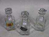 three small glass bottles with gold and silver items in them