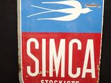 une enseigne indiquant « Concessionnaire Simca » sur laquelle figure un oiseau