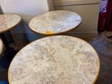 trois tables rondes en marbre avec des pieds noirs dans une pièce
