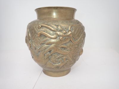 un vase doré orné d'un dragon sur un fond blanc