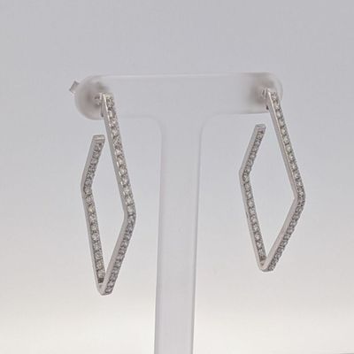 une paire de boucles d'oreilles en diamant posée sur un présentoir, sur fond blanc