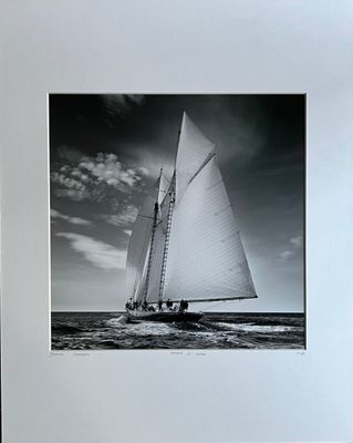 black and white photograph of a sailboat in the ocean under a cloudy sky