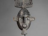a wooden mask with horns on a stand on a gray background