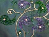 purple and green embroidered flowers and leaves with pearls on a green background