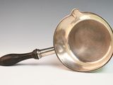 an old silver frying pan with a wooden handle on a white surface